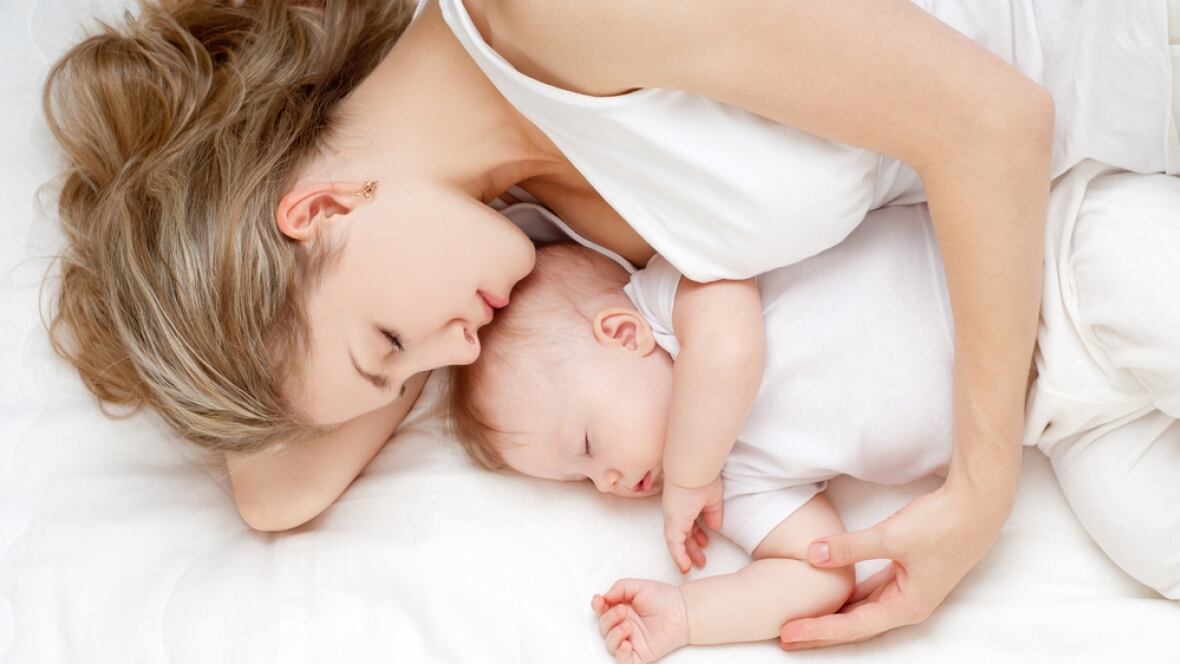 Mother sleeping peacefully with her baby – natural ways for new parents to improve sleep quality without pills.